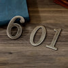 Magnetic silver house number featuring the digits 601 embossed on a dark wooden surface.