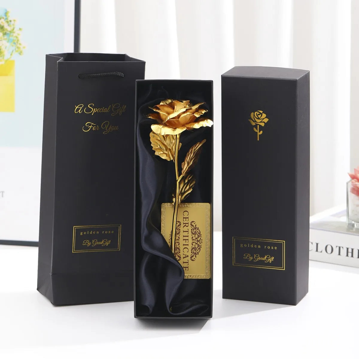 Three black gift boxes with gold foil roses and certificates displayed on a white surface.