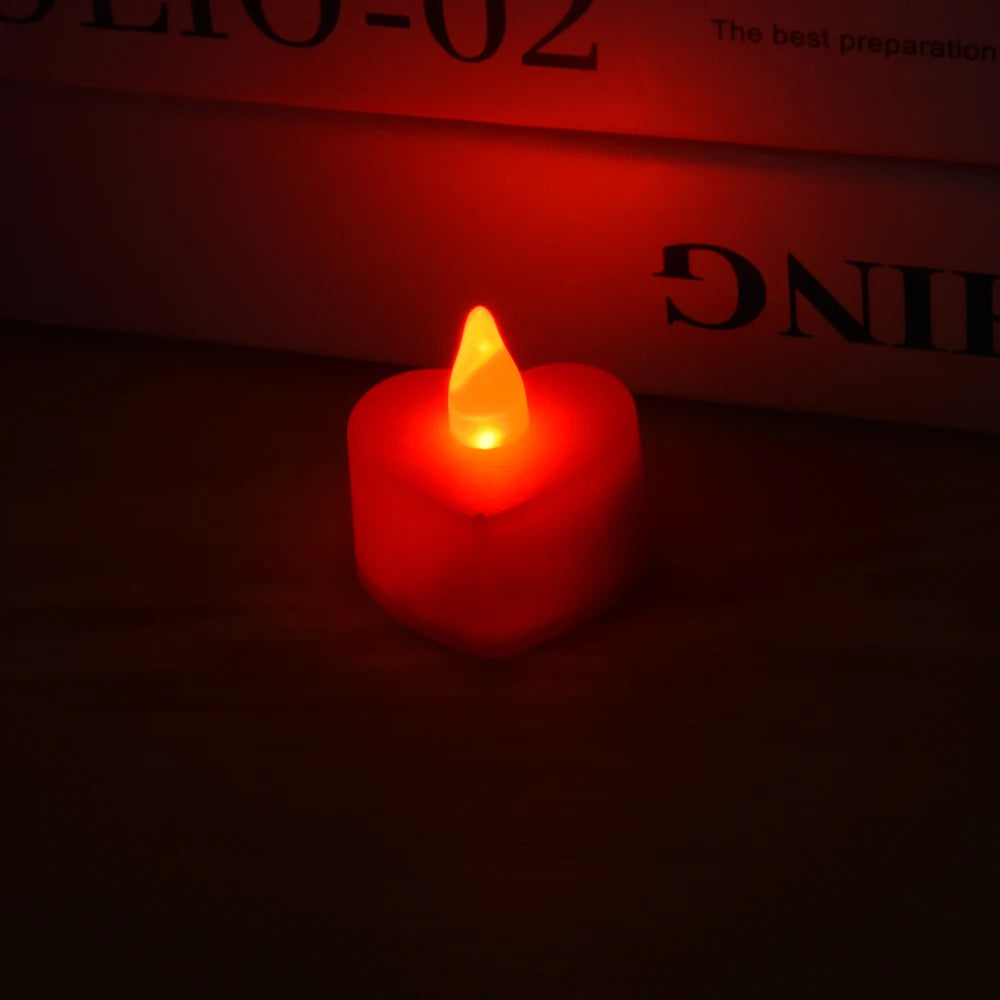 A glowing red heart-shaped LED tealight candle resting on a dark surface.