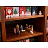 A wooden shelf displays a miniature nativity scene set with figurines of Mary, Jesus, a shepherd, and an animal in an iron bo