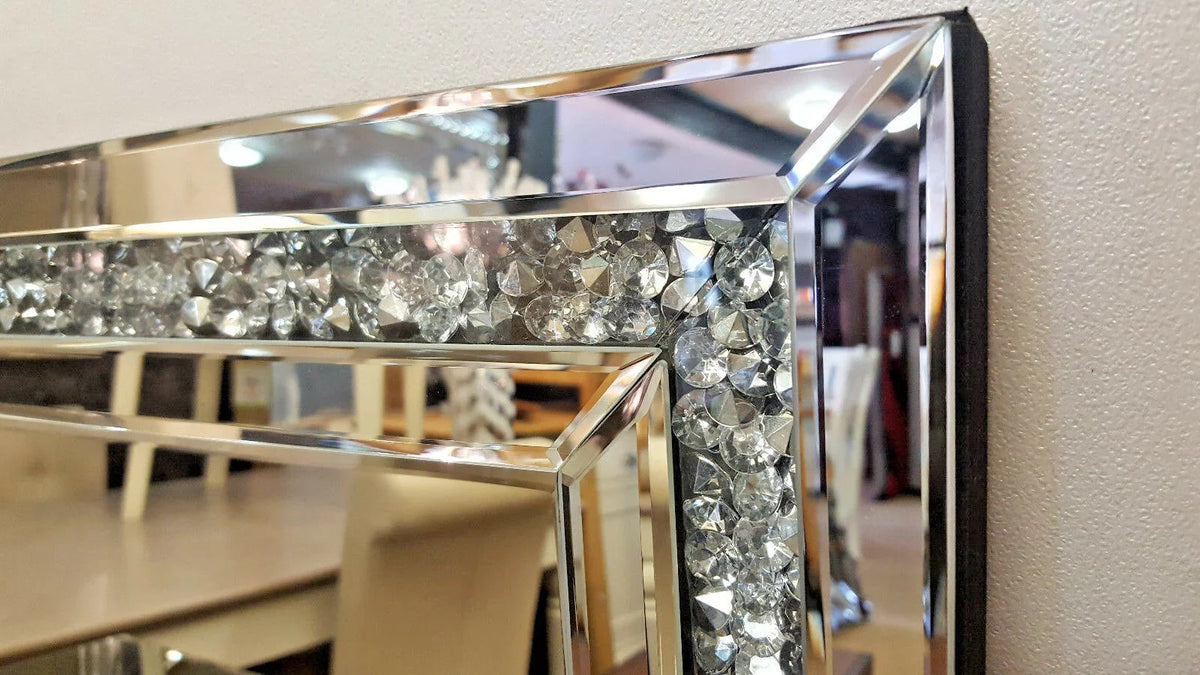 A silver crystal beveled wall mirror with a faceted design reflecting an interior setting.