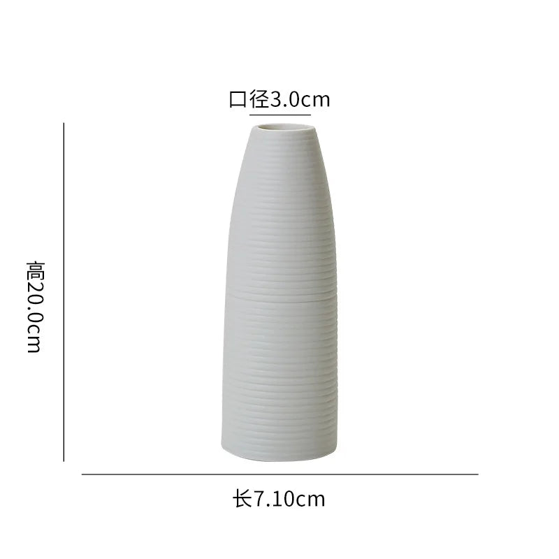 A tall, white ceramic desktop vase with an organic ripple design.