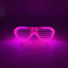 Pink leuchtende herzförmige LED-Partybrille leuchtet hell vor dunklem Hintergrund
