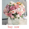 A lush bouquet of artificial roses and flowers in shades of pink, peach, and mauve arranged in a clear glass vase.