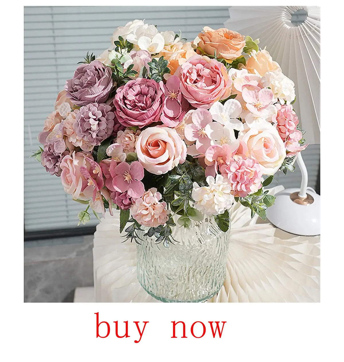 A lush bouquet of artificial roses and flowers in shades of pink, peach, and mauve arranged in a clear glass vase.