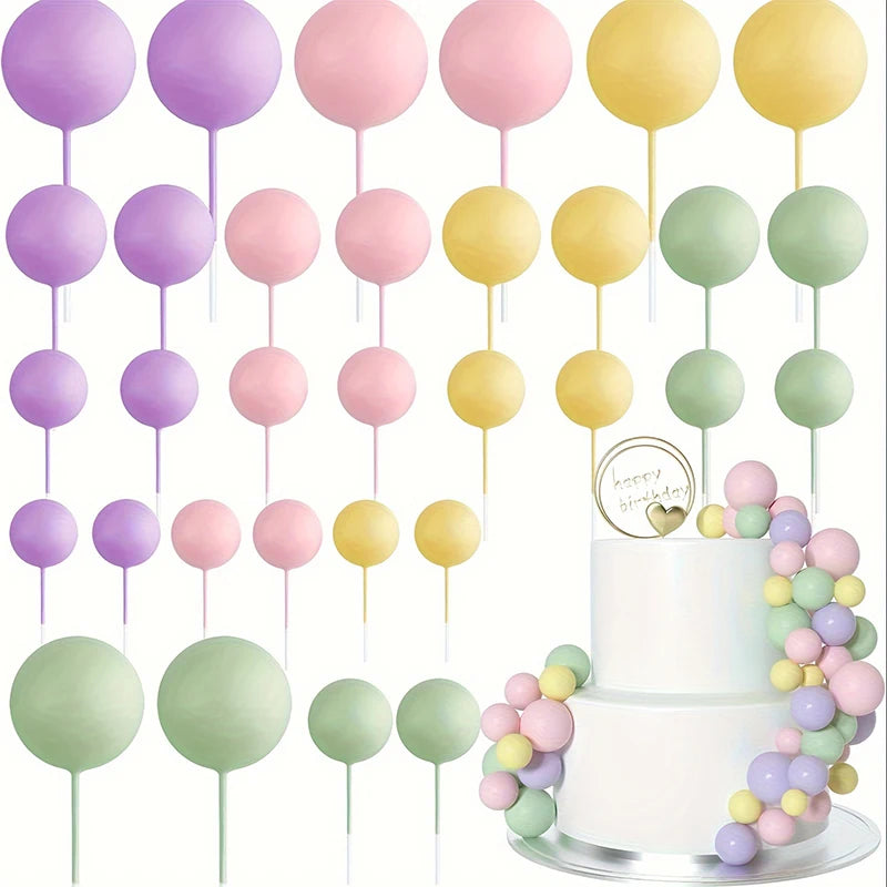 A set of twenty pastel colored ball cake toppers on sticks arranged around a two-tiered white cake.