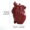 A reddish-brown heart-shaped resin sculpture used as a tabletop vase.