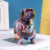 A colorful resin figurine of a dachshund dog in various vibrant colors sitting on a white box.
