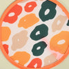 A round fabric hand fan featuring an orange border and a pattern of abstract shapes in orange, beige, and dark green.