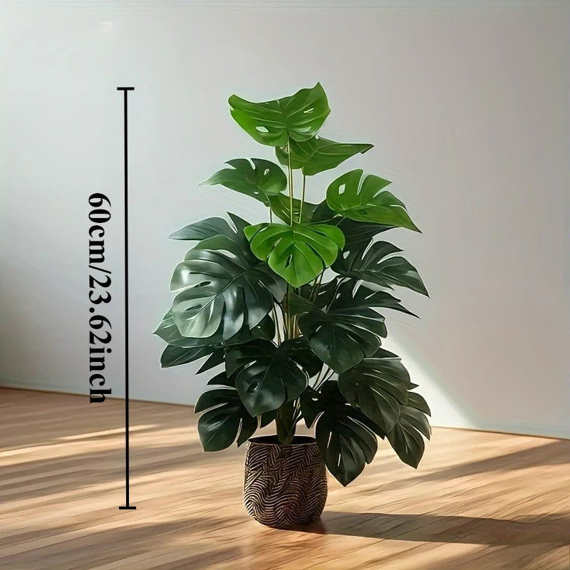 A lush green artificial monstera palm plant in a pot displayed against a white wall with a measuring stick.