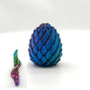 A close-up view of a blue dragon egg fidget toy with iridescent scales and a smaller version.