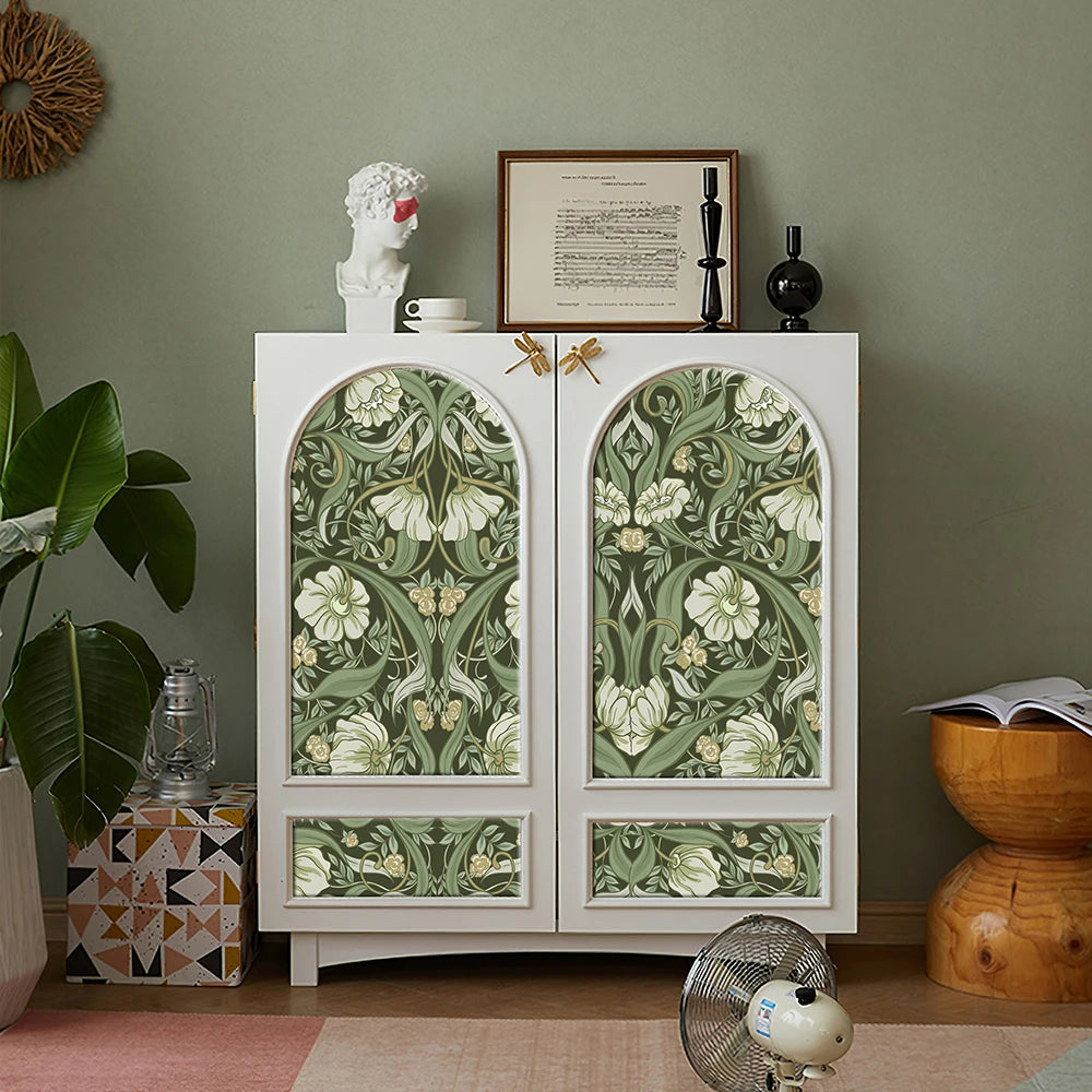 Armoire blanche avec portes arquées, papier peint floral vert et accents décoratifs.