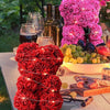 Eine Anordnung künstlicher rote und rosa Rosen in Sträußen und Girlanden auf einem Holztable.