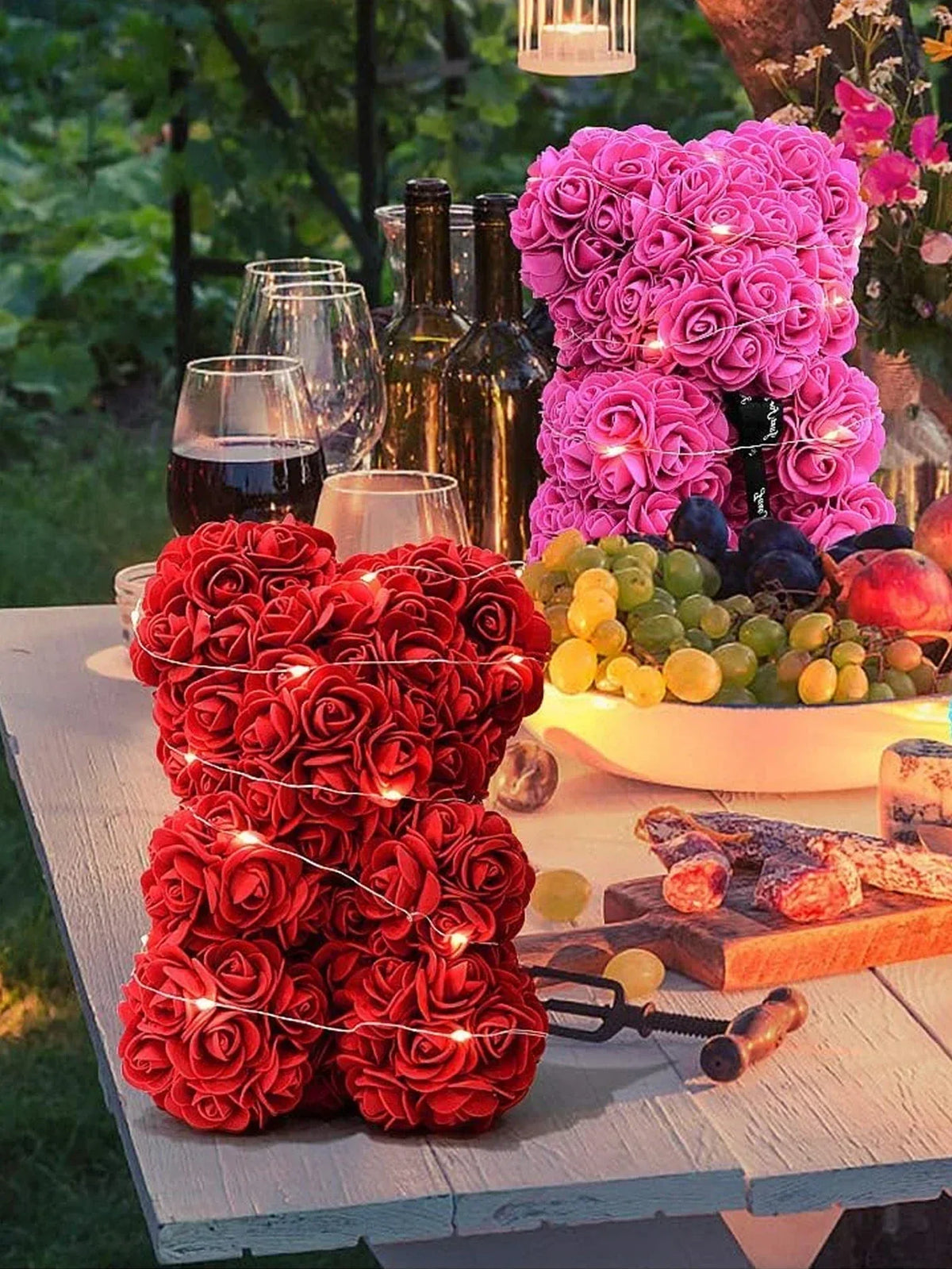 Eine Anordnung künstlicher rote und rosa Rosen in Sträußen und Girlanden auf einem Holztable.
