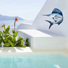Blue and silver metal fish wall art mounted on a white stucco wall above a swimming pool.
