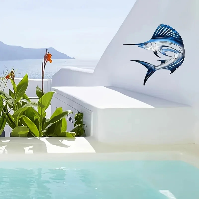 Blue and silver metal fish wall art mounted on a white stucco wall above a swimming pool.
