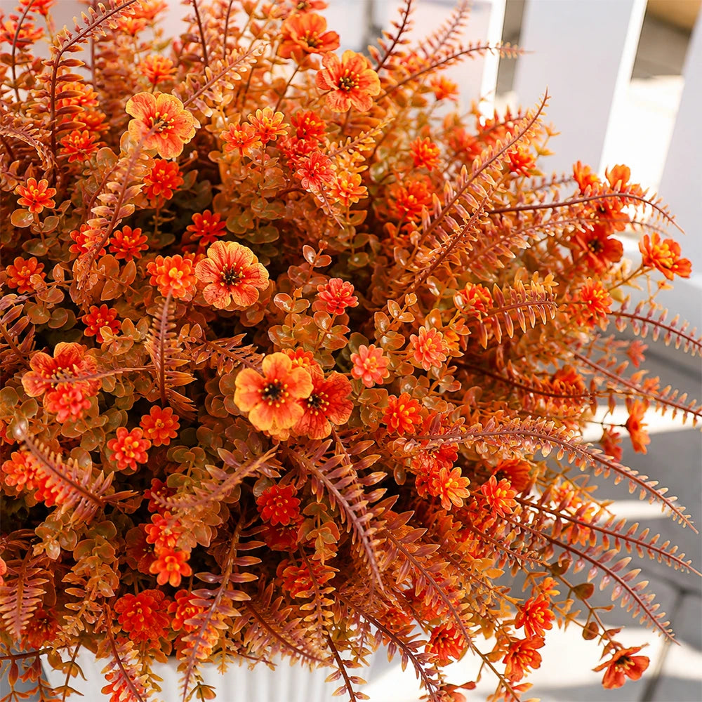 Ein Strauß künstlicher Herbstblumen in Orange- und Rosttönen, arrangiert für Herbstdekoration.