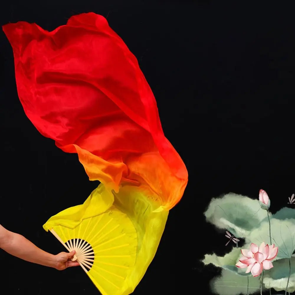 A hand holds a large, vibrant red and yellow silk ribbon dance fan against a black background.