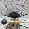 An elegant vintage Chinese folding hand fan with a black frame and silver-edged paper is displayed on a wooden stand.