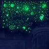 A dark room decorated with glowing green stars, planets, and a silhouette of a cat on the wall.
