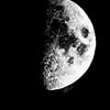 A minimalist black and white print of a bright, textured moon phase against a dark background.