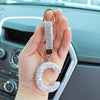 A hand holds a crystal letter keychain charm with a gold clasp and a sparkling letter C.
