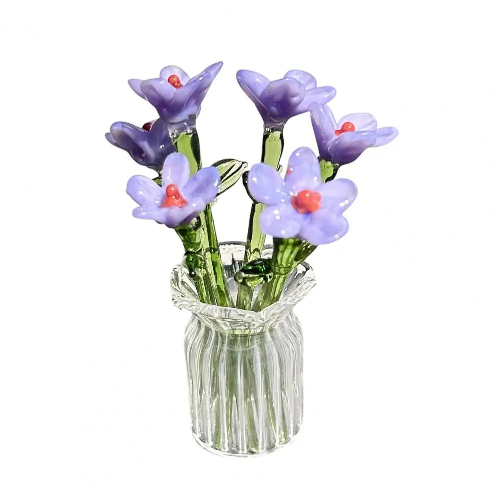 A bouquet of hand-blown glass purple flowers in a clear glass vase.