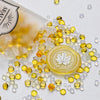 A pile of clear and yellow wax sealing beads scattered on a white surface next to a plastic container.