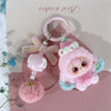 A pink fluffy heart plush keychain charm with a pink ring and a green accent.