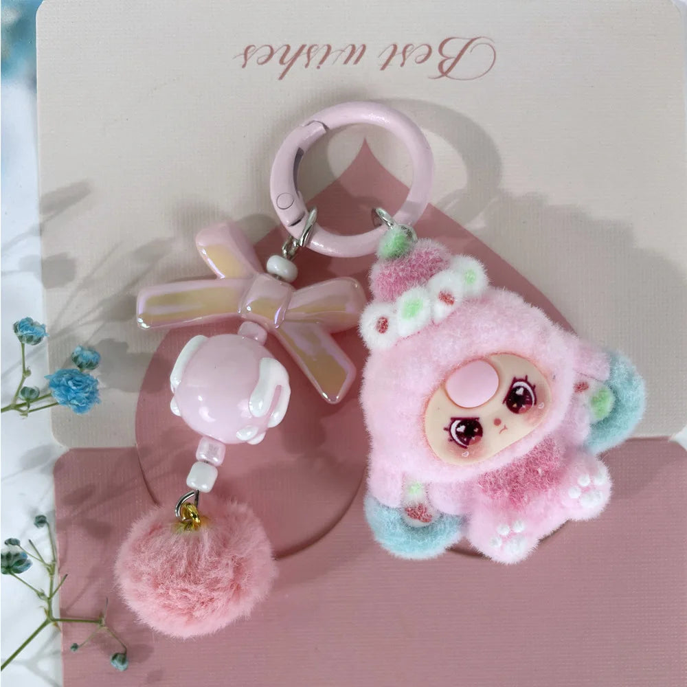 A pink fluffy heart plush keychain charm with a pink ring and a green accent.