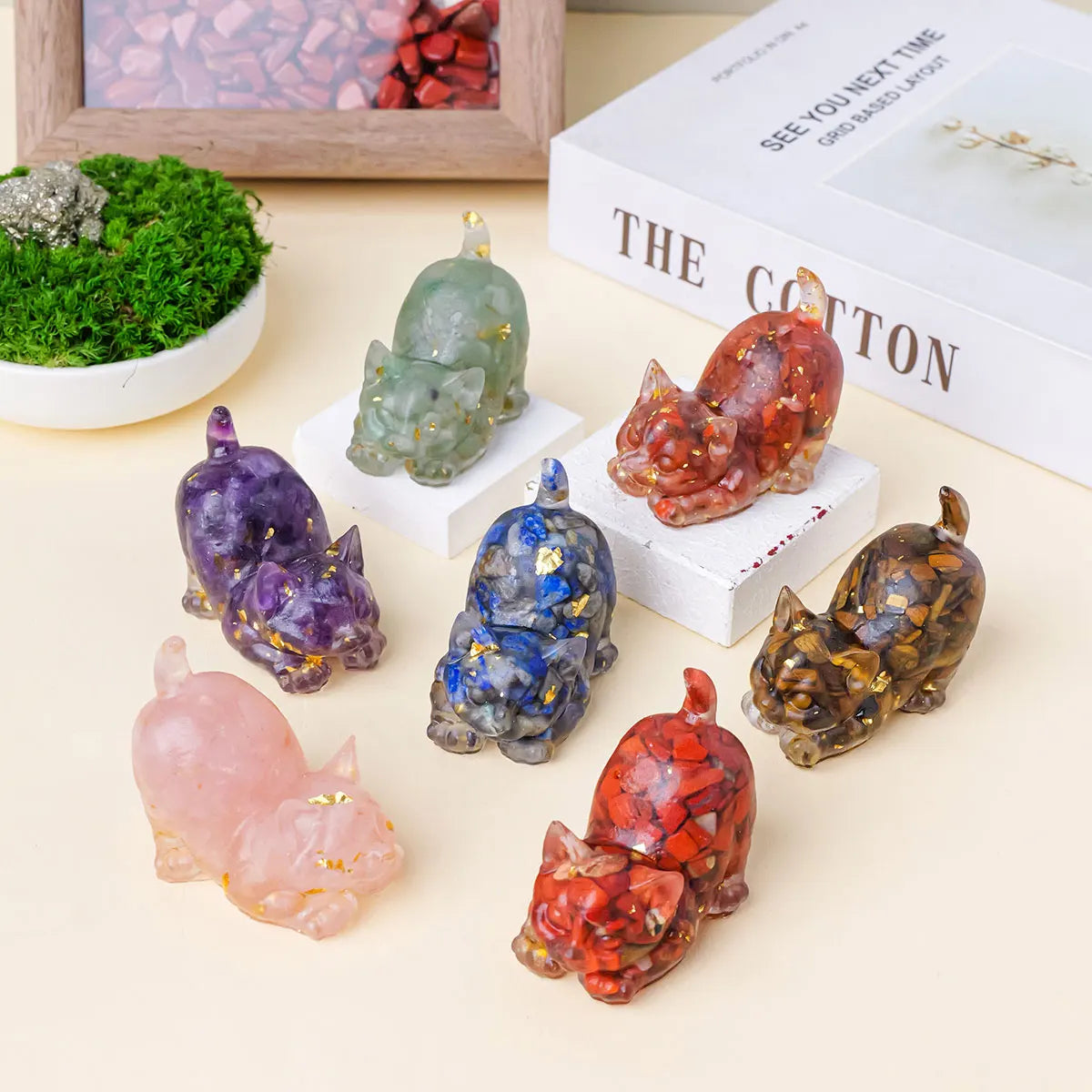 A collection of natural crystal cat statues in various colors and textures displayed on a light background.