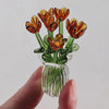 A hand-blown glass flower bouquet featuring orange and yellow tulips in a clear glass vase.