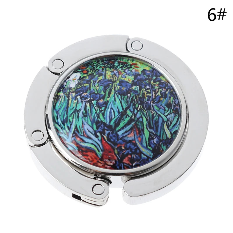 A silver foldable handbag hook with a circular opening and hinged design.