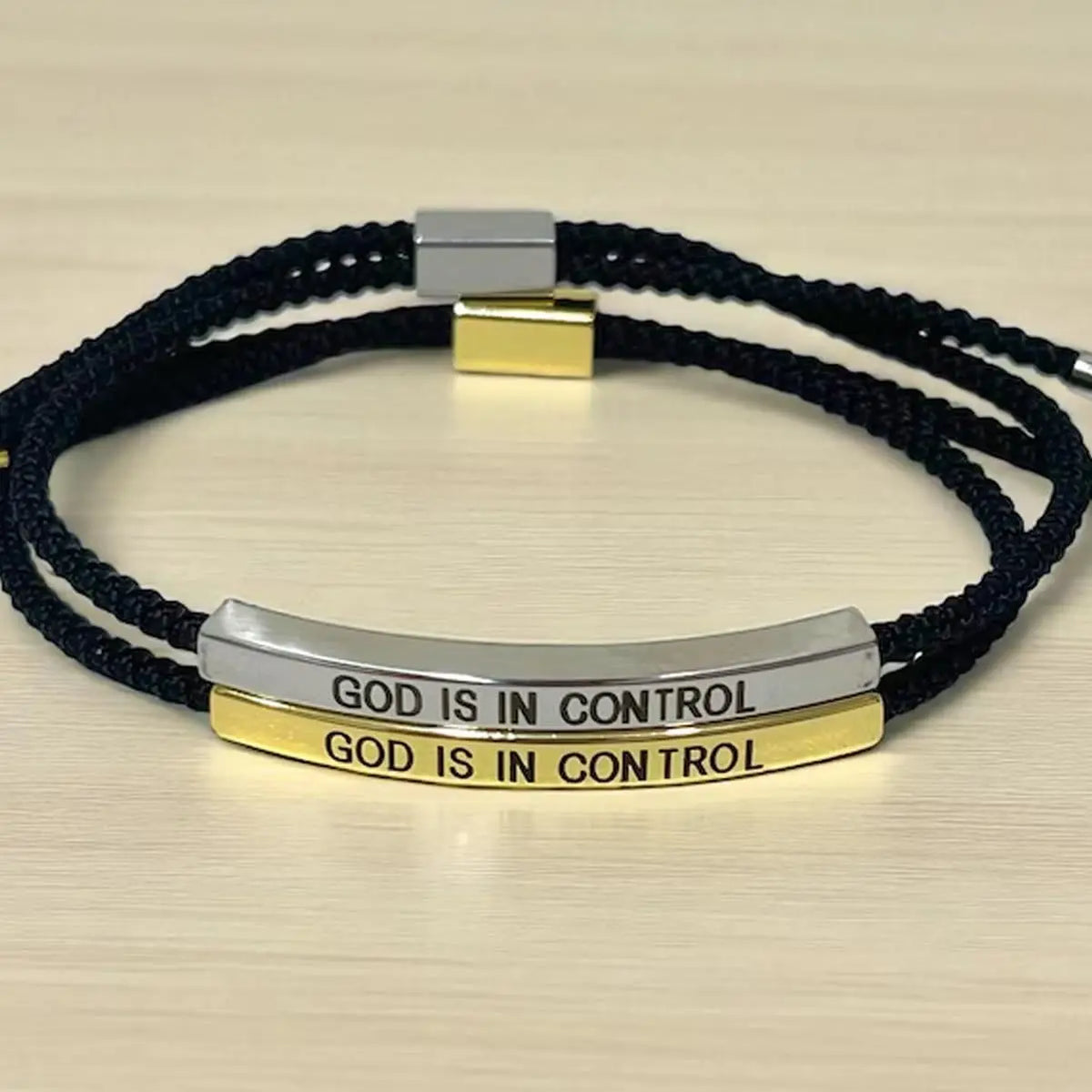 A black beaded bracelet with silver and gold metal accents engraved with the phrase God is in control