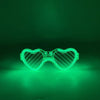 Fluoreszierende herzförmige LED-Partybrille leuchtet hellgrün vor dunklem Hintergrund.