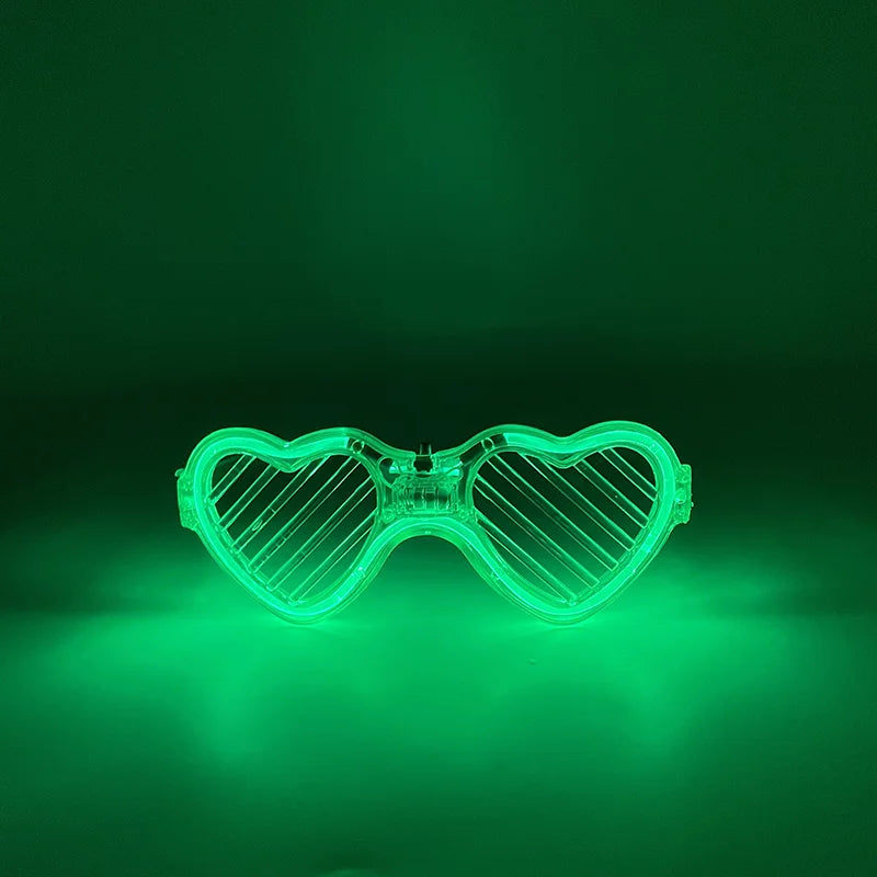 Fluoreszierende herzförmige LED-Partybrille leuchtet hellgrün vor dunklem Hintergrund.