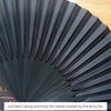 A close-up of a black folding hand fan with bamboo ribs, showing the pleated surface and texture.