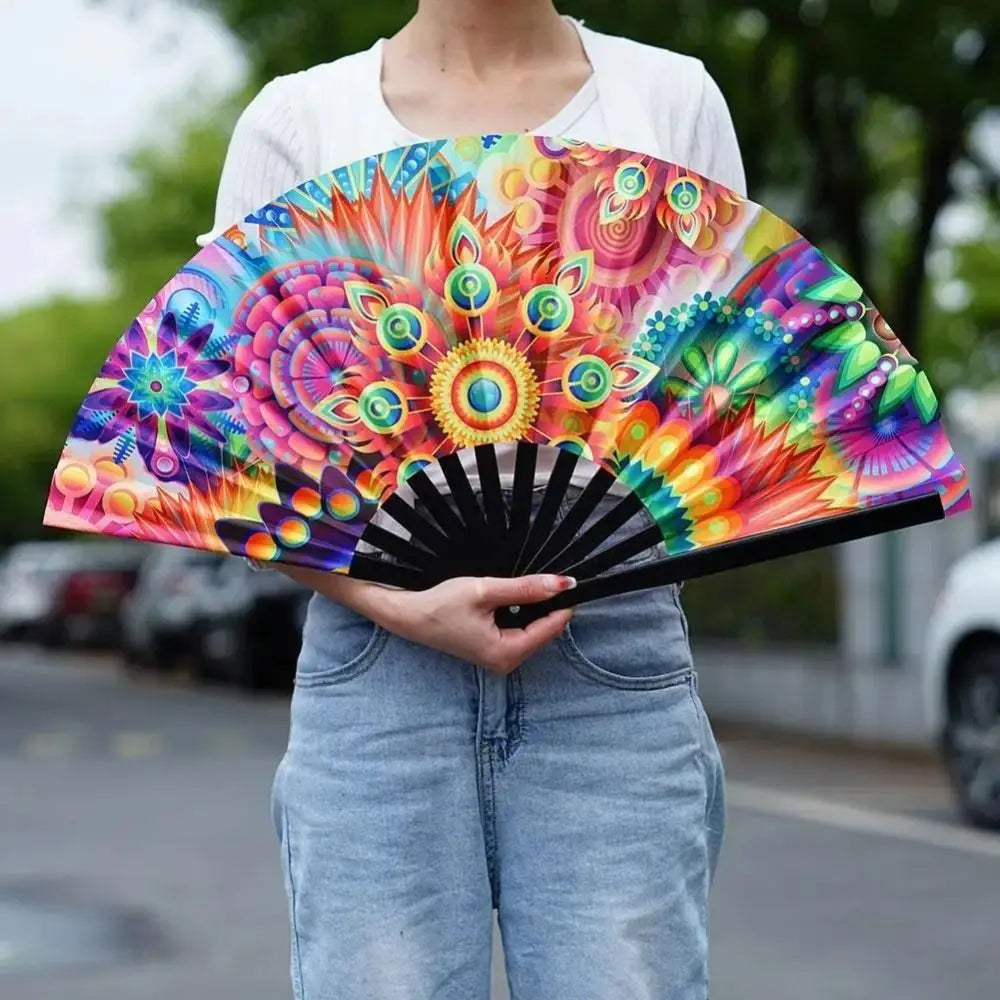 A person holds a vibrant UV fluorescent handheld folding fan with colorful floral patterns.