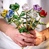 Handcrafted crystal glass rose vase with golden leaves held in a person's hands.