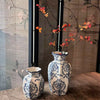 A pair of hand-painted blue and white porcelain vases displayed on a wooden surface against a textured background.