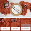 A set of terracotta semi-sheer cheesecloth table runners featuring rose floral accents and perfectly finished edges.