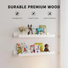 A set of two white wooden floating shelves displaying children's books and decorative items.