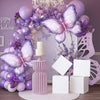 A purple butterfly balloon arch kit featuring balloons, flowers, and a tiered cake decoration for a party.