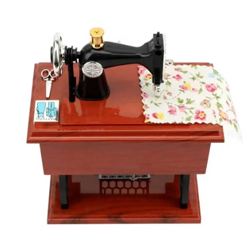 A vintage sewing machine music box with a black body and brass accents resting on a wooden base.