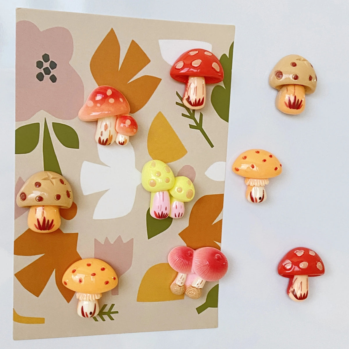 A set of nine colorful, cute decorative mushroom fridge magnets on a light background.
