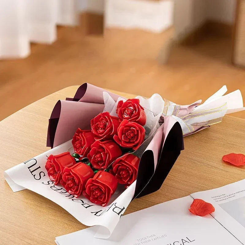 A bouquet of red roses wrapped in pink and black paper, displayed on a wooden surface.
