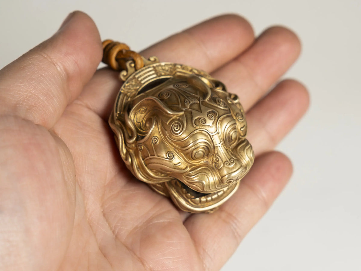 A hand holds a pure copper lucky tiger head bell for Feng Shui decor.