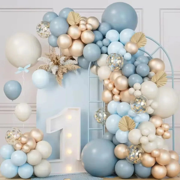 A large arrangement of latex balloons in blue, sand, white, and gold forming a wreath or floral display.