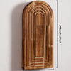 Jarrón de pared vertical de madera arqueada con estrías concéntricas, montado en una pared blanca.
