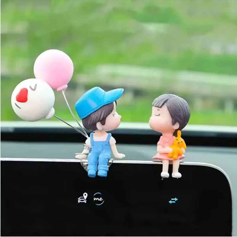 A cute couple figurine with a balloon is displayed on a car dashboard.